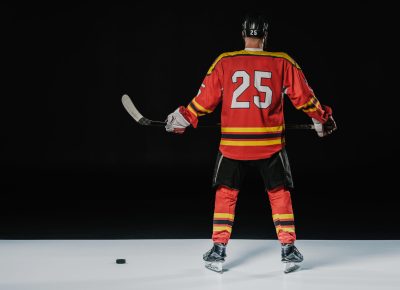 back view of professional ice hockey player holding hockey stick on black