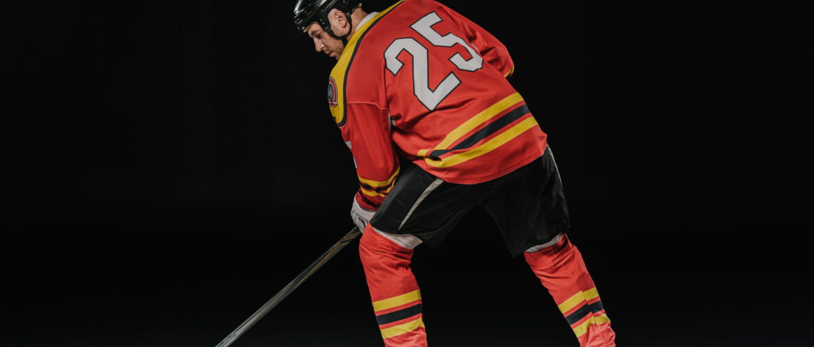back view of professional sportsman playing ice hockey on black