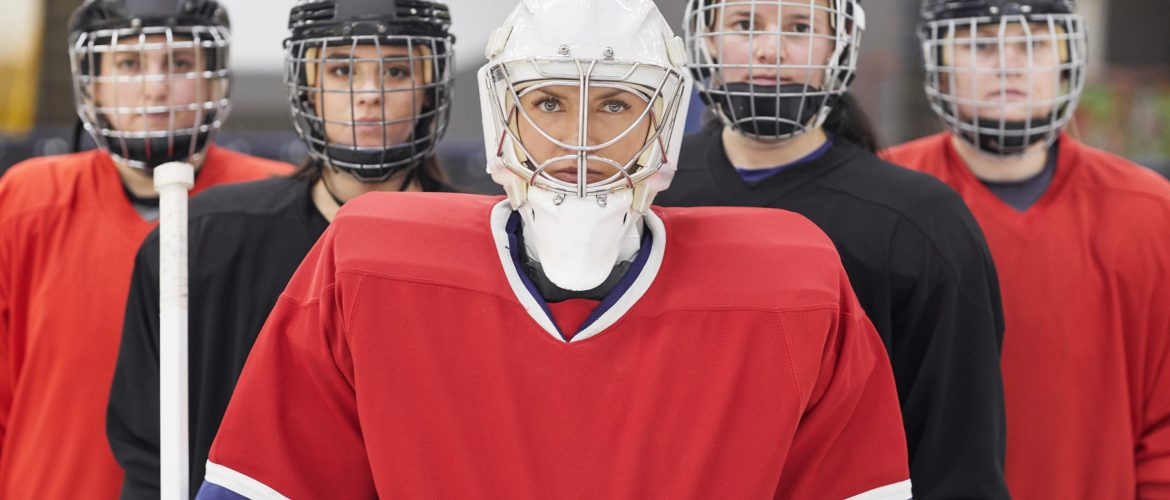 Waist up portrait of female hockey team looking at camera while posing during match