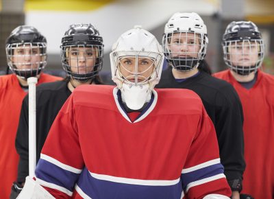 Waist up portrait of female hockey team looking at camera while posing during match